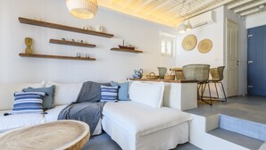 A modern living room with a sofa, coffee table, and decorative shelves. - Mykonos Perla Town House - Perfect Location with Pool and Private Parking - 2 BR (Mykonos)