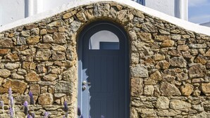 A building with a stone facade and a dark door, surrounded by lavender plants. - Mykonos Perla Town House - Perfect Location with Pool and Private Parking - 2 BR (Mykonos)