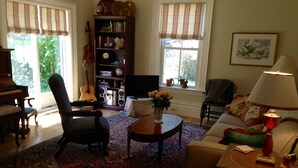 Un salon avec un piano, une bibliothèque, un téléviseur et un canapé.