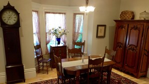 Une salle à manger avec une table en bois, des chaises, un tapis, une horloge et un buffet.