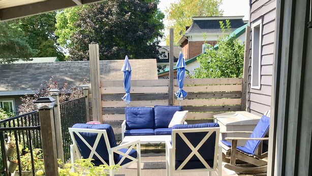 Une terrasse en bois aménagée avec du mobilier d’extérieur, notamment un canapé et des fauteuils, ainsi que des plantes en pot.