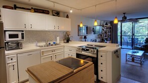 A modern kitchen with white cabinetry, a built-in oven, and a wooden island. - Kona Pacific B311 - Quiet, comfortable & walking distance to Town and the beach (Kailua Kona)