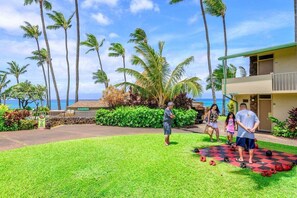 A hotel with a checkered outdoor area, palm trees, and a view of the ocean.