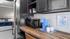 Una cocina pequeña con armarios oscuros, encimera de madera y cafetera.