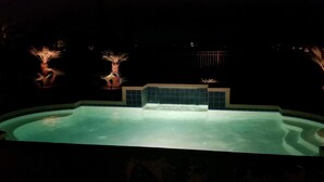 Ein Schwimmbecken mit gefliestem Rand und einer zentralen Wasserspielanlage.