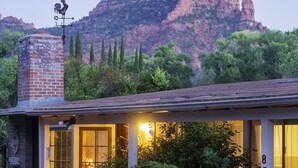 A rustic building with a chimney, a porch, and a view of a mountain.