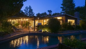A modern house with a swimming pool, outdoor seating, and a covered patio area.