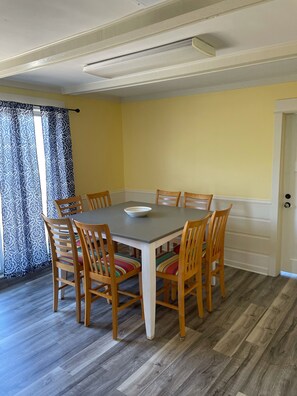 A dining area with a table and chairs, a patterned curtain, and a door. - Historic downtown 3 bedroom close to everything!!! (Grand Haven)