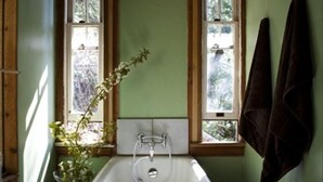 A bathroom with a freestanding bathtub, two windows with wooden frames, and a towel hanging on the wall. - A Happy Nest up in the trees, unique Salt Spring Cottage close to town (Salt Spring Island)