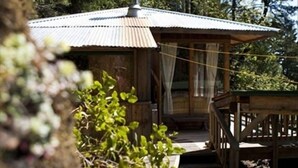 A rustic cabin with a metal roof, wooden deck, and a chimney. - A Happy Nest up in the trees, unique Salt Spring Cottage close to town (Salt Spring Island)