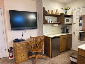 A compact kitchen with a flat-screen TV, wooden cabinets, a microwave, and a dishwasher. - Relaxing Retreat in Ivins — Near Snow Canyon & Tuacahn Amphitheatre (Ivins)