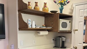 Una cocina compacta con armarios de madera, microondas integrado, lavavajillas y una pequeña encimera.