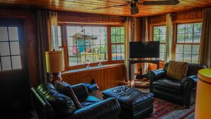 A cozy living room with leather sofas, a television, and a ceiling fan.