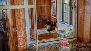 A rustic wooden room with a window, a coffee maker, and a glass on the counter.