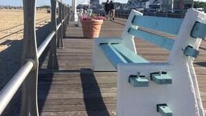 Un muelle de madera con un banco, barandillas metálicas y plantas en macetas.