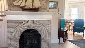Una sala de estar con chimenea, un modelo de barco y un sillón azul.