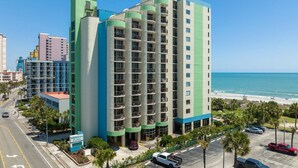 A multi-story hotel with balconies, located near a beach with a clear view of the ocean. - Newly renovated, modern, ocean front, prime location!  Walk to everything! (Myrtle Beach)