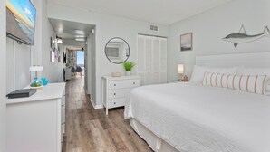 A bedroom with a large bed, a desk with a computer, a mirror, and a wall-mounted fish decoration. - Newly renovated, modern, ocean front, prime location!  Walk to everything! (Myrtle Beach)