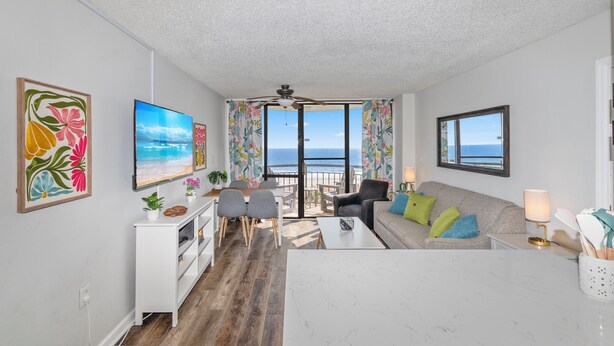 A modern living room with a view of the ocean, a ceiling fan, and a dining area with a view. - Newly renovated, modern, ocean front, prime location!  Walk to everything! (Myrtle Beach)