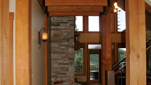 A wooden interior with a stone wall, a staircase, and a view of the outdoors.