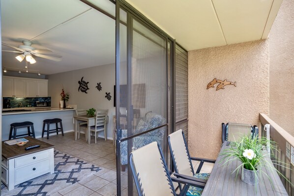 A balcony with a table, chairs, and a potted plant.