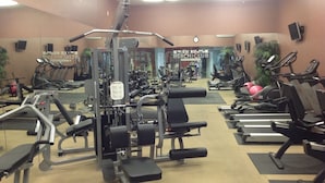 Une salle de sport équipée de divers appareils d’exercice, notamment des tapis de course, des appareils de musculation et des poids libres.