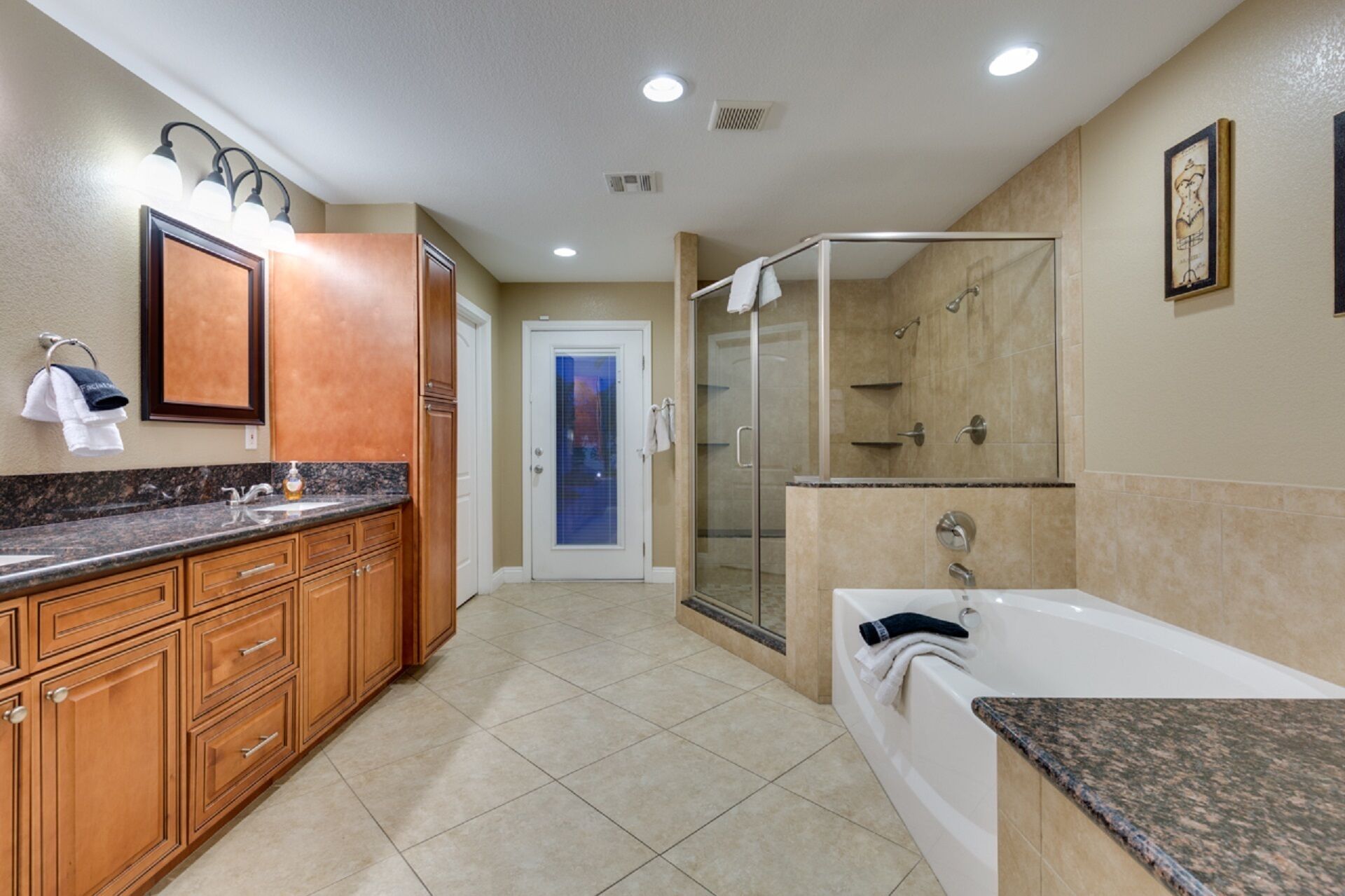 A modern bathroom with a walk-in shower, a bathtub, and a vanity with a granite countertop.