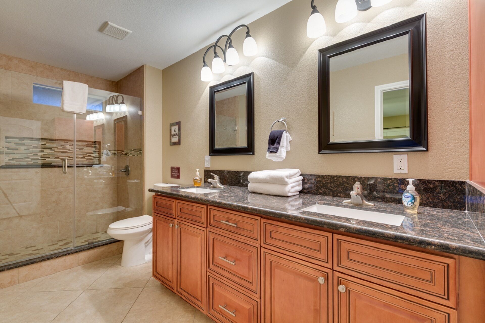 A modern bathroom with a large vanity, double sinks, a glass shower enclosure, and a large mirror.