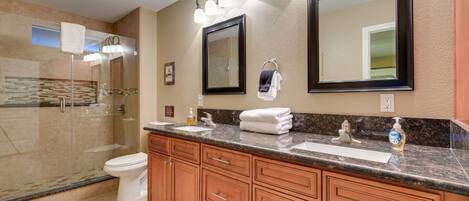 A modern bathroom with a large vanity, double sinks, a glass shower enclosure, and a large mirror.
