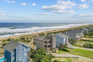 A coastal residential area with houses near the beach, featuring a pool and a view of the ocean.