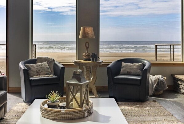 Habitación con vista a la playa, que incluye dos sillones de cuero, una mesita con lámpara y un farol decorativo.
