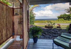 A wooden deck with a bench and a potted plant, overlooking a lava field and ocean view. - Stunning Ocean Views - Whale House Hawaii (Hilo)