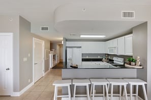 Enjoy cooking in this well-equipped kitchen with a central island, white cabinetry, and stainless steel range hood.