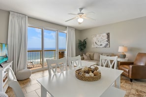 Relax in this spacious living room with a dining table, comfortable sofa, and armchair, plus a balcony with ocean views.