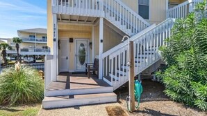 Une maison à deux étages avec un porche à l’avant, un escalier et une petite terrasse.