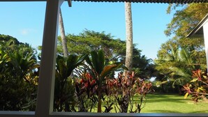 Un espace extérieur abrité offrant une vue sur une pelouse bien entretenue et une végétation tropicale.
