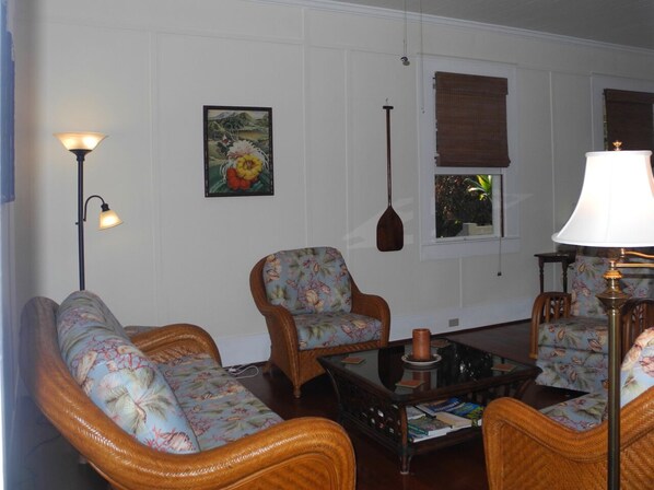 A living room with wicker furniture, a coffee table, and a painting on the wall.