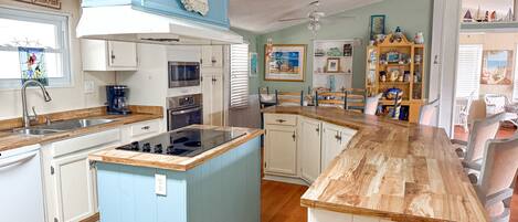 A kitchen with a central island, built-in appliances, and a dining area with chairs.