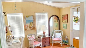 A cozy room with wicker furniture, a wooden floor, and nautical decor including model ships and a lighthouse. - Resort community, 6seater golf cart, dog friendly. Message for discount (Surfside)