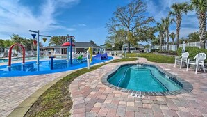 A pool area with a hot tub, lounge chairs, and a slide. - Resort community, 6seater golf cart, dog friendly. Message for discount (Surfside)