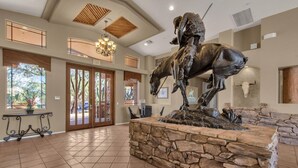 A lobby with a stone wall centerpiece featuring a horse statue, large windows with blinds, and a chandelier. - Resort-like 2BR/2BA townhome in sunny Scottsdale near golf, hike, dine, shop etc (Scottsdale)