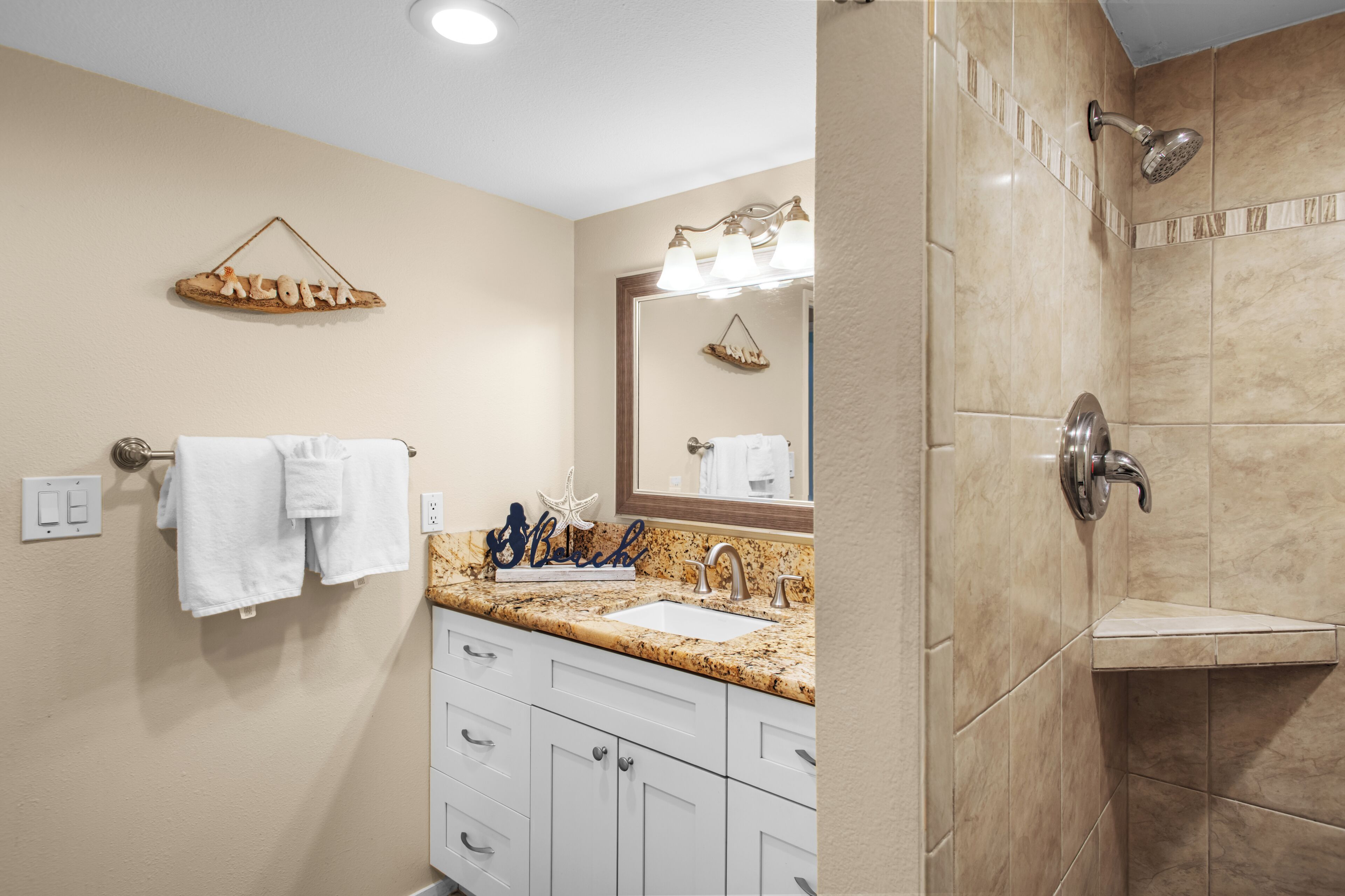 A bathroom with a sink, mirror, towel rack, and shower.