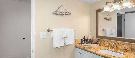 A bathroom with a sink, mirror, towel rack, and decorative wall items.