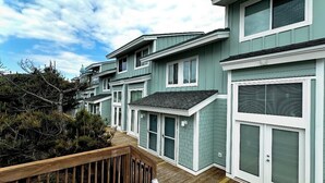 A row of modern, light green houses with white trim and large windows.
