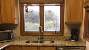 A kitchen with wooden cabinets, a stainless steel sink, a coffee maker, and a dishwasher.