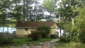 A house with a stone pathway leading to the front door, surrounded by trees and a fence. - Peaceful Lakefront 3 bedroom Cottage On Quiet Forest Lake  (Gray)