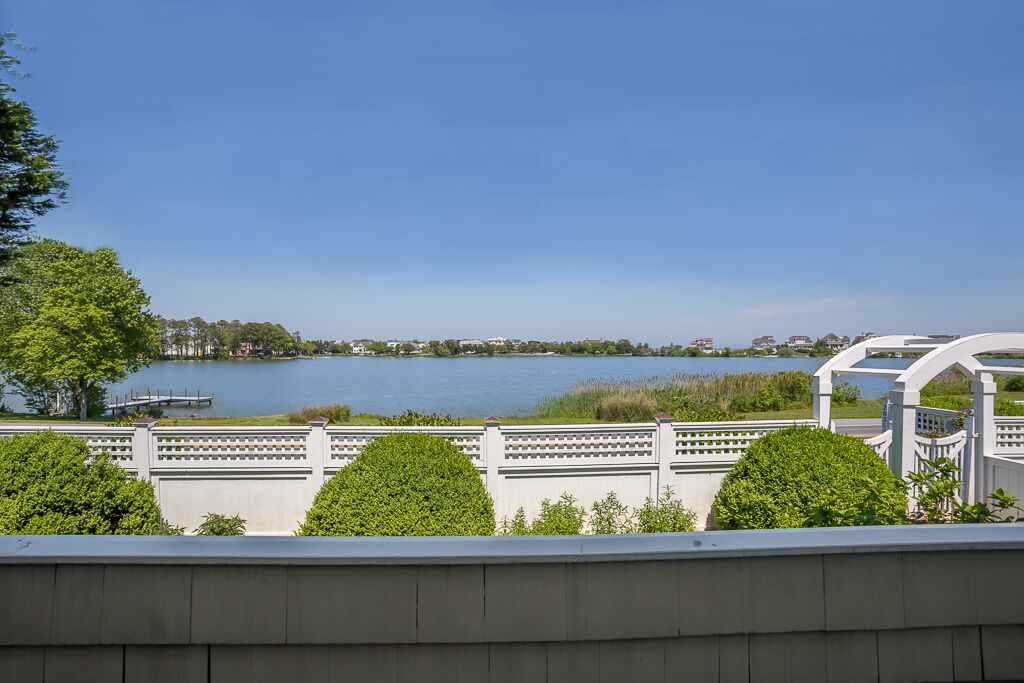 A lakeside view with a gazebo and a white fence.