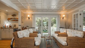 A spacious living area with wicker furniture, a dining table, and a view through large glass doors. - Rehoboth Beach Lake Front Private Pool Home Sleeps 12 (Rehoboth Beach)