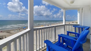 A balcony with a view of the beach and ocean.