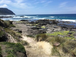 A rocky coastal path leading to the sea with a clear view of the ocean and a distant hill. - Single level home, near beach. Ultra clean. Great location -Walk to everything! (Yachats)